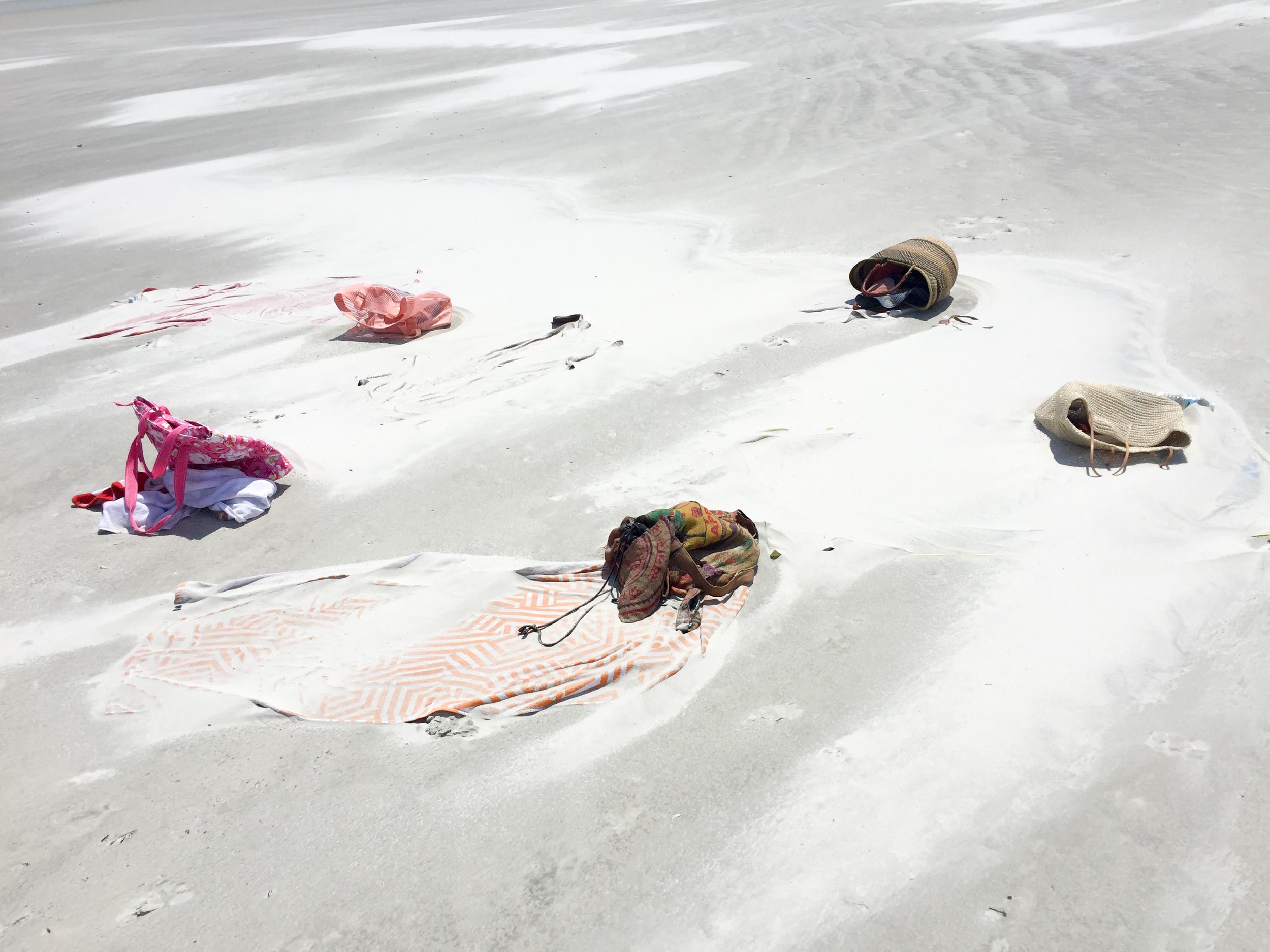 This is what our stuff looked like after we left it for a 30 minute beach walk- yes there are towels under there... The bag my sister got me from Target (all the way to the right) still looked great even though it drowned in sand. 