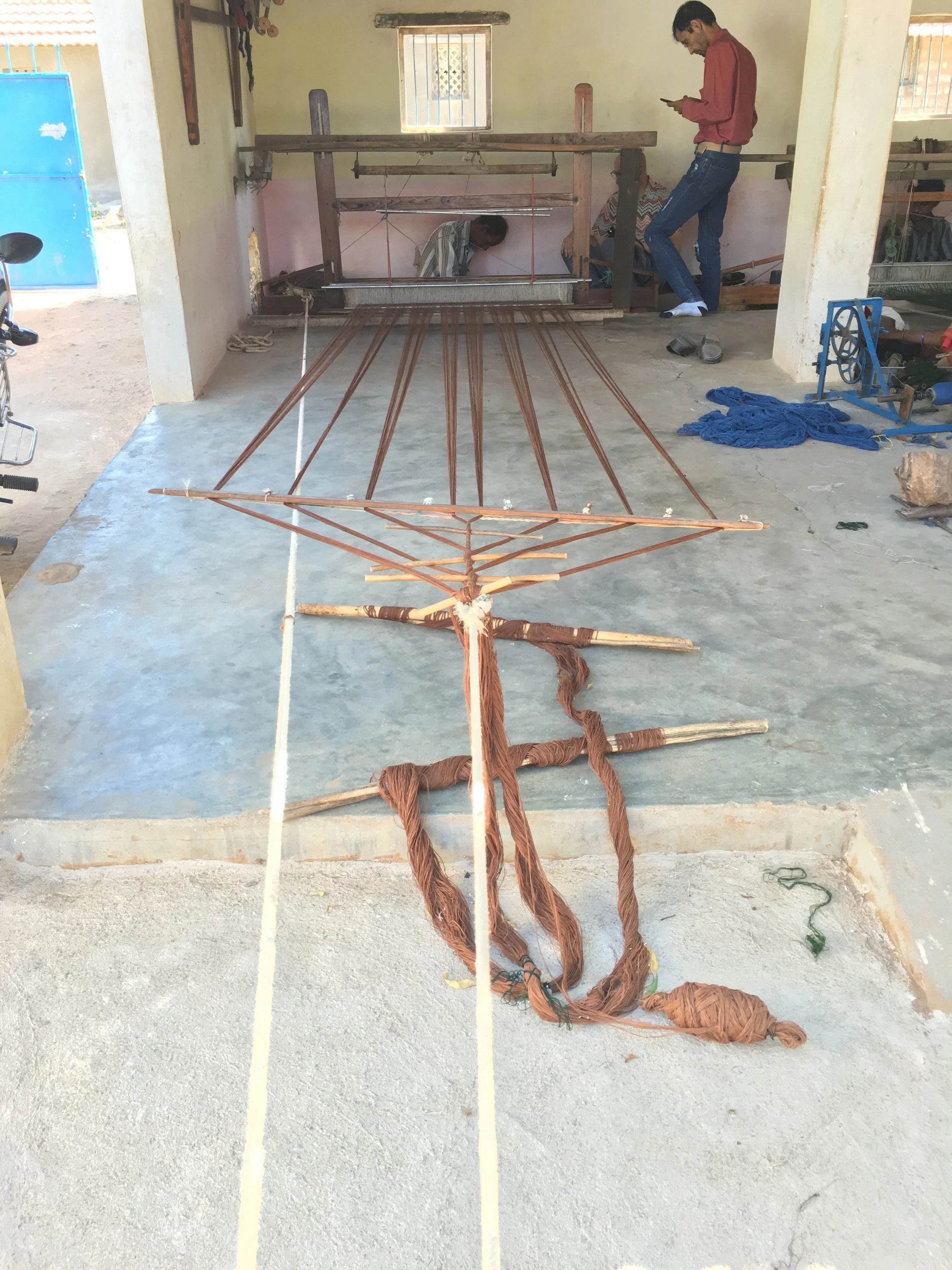 The weavers work on traditional pit looms