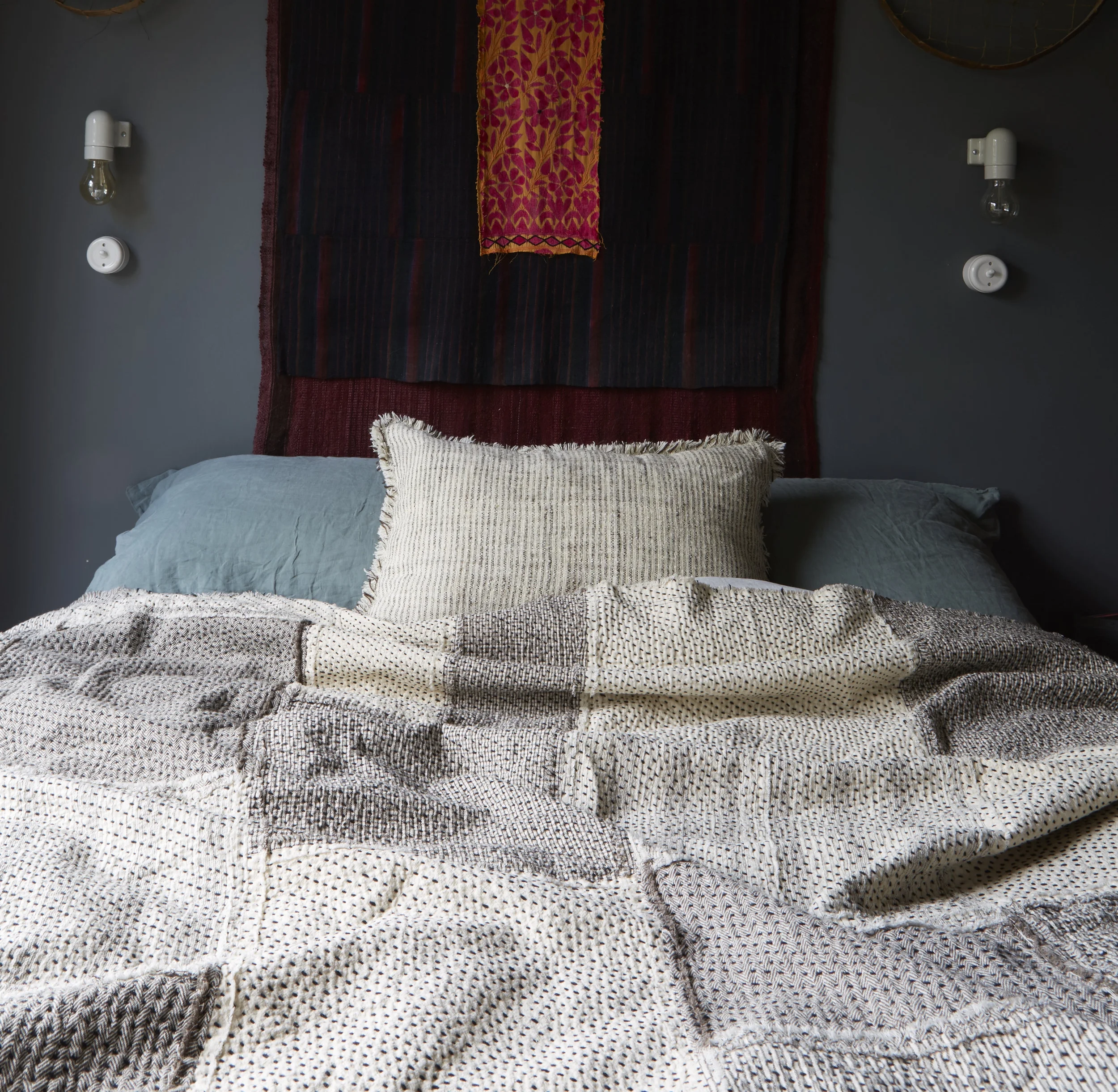 A Stitch by Stitch Raw Chindi Quilt adds light and texture to this bedroom with dark grey green walls