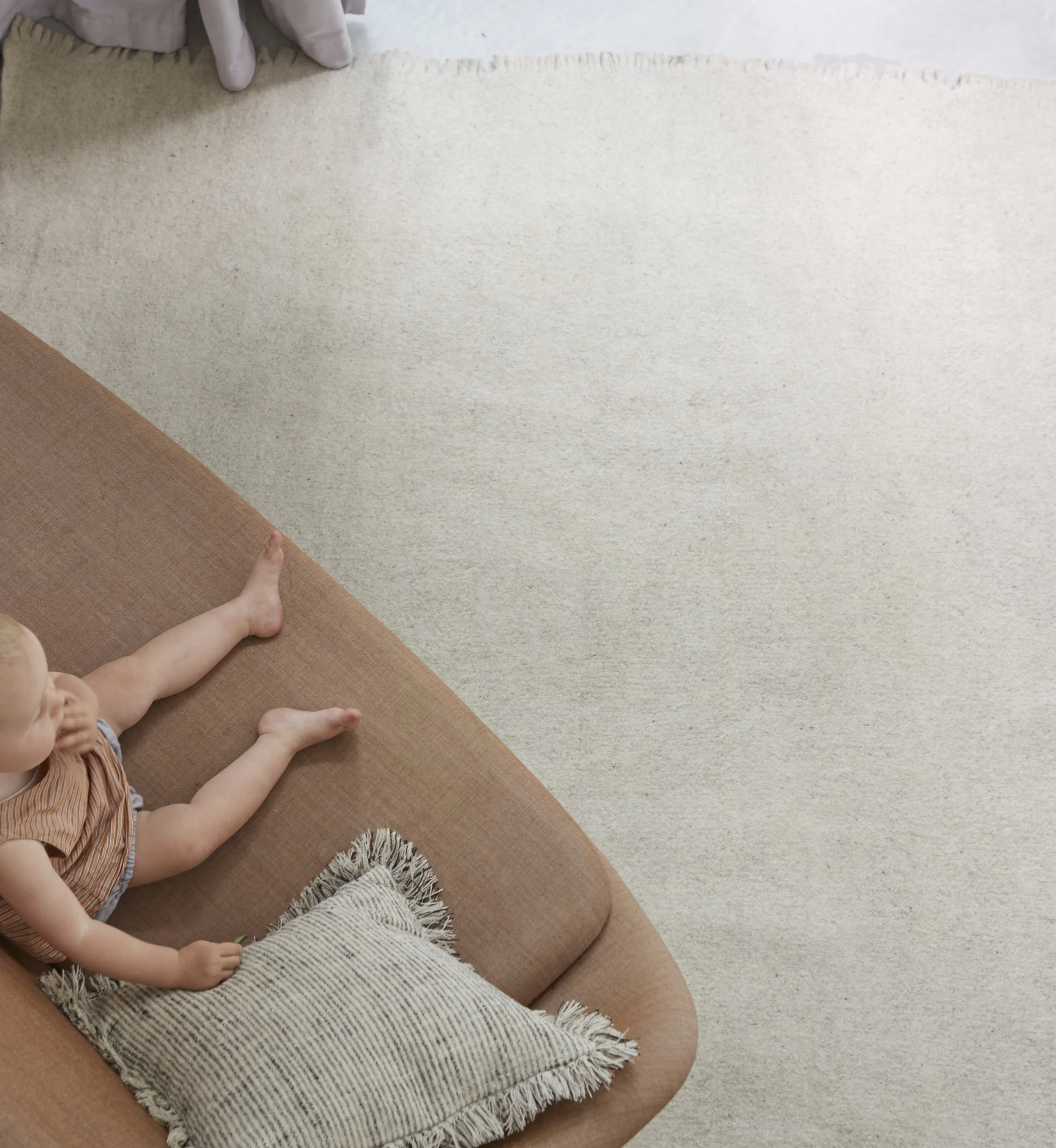White wool rug in modern house with baby on sofa