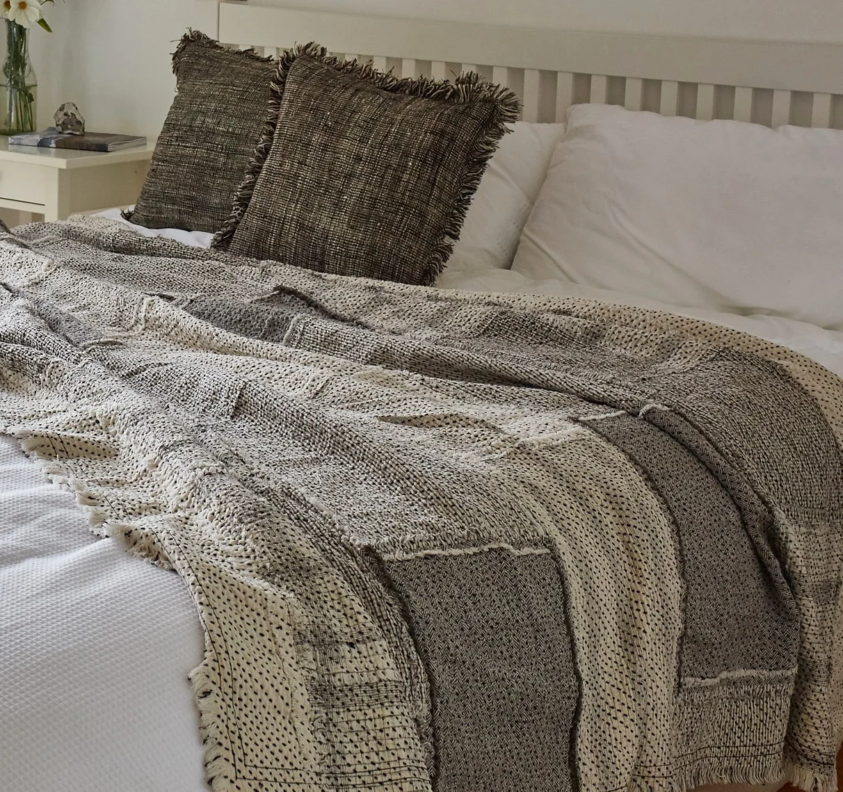 Textured minimal style throw on wooden bed in modern white bedroom