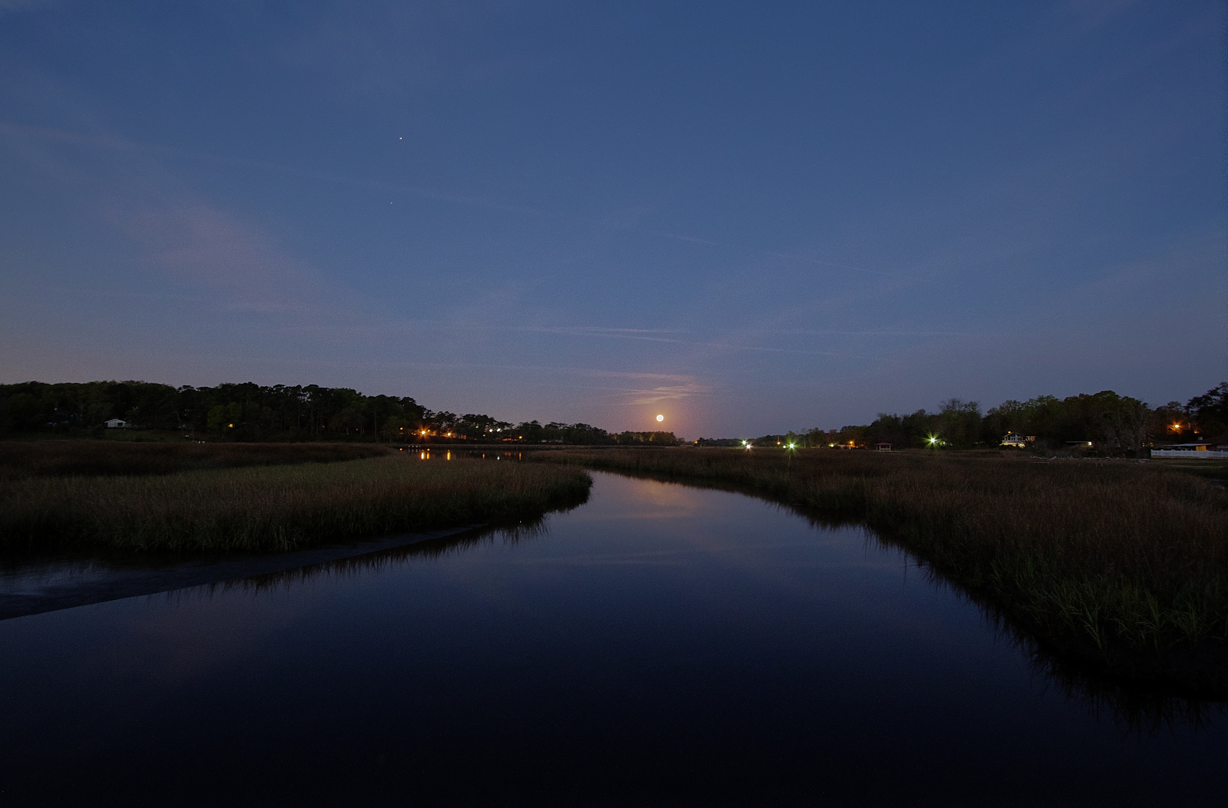 The setting full moon pulls the curtain of night below the western horizon.
