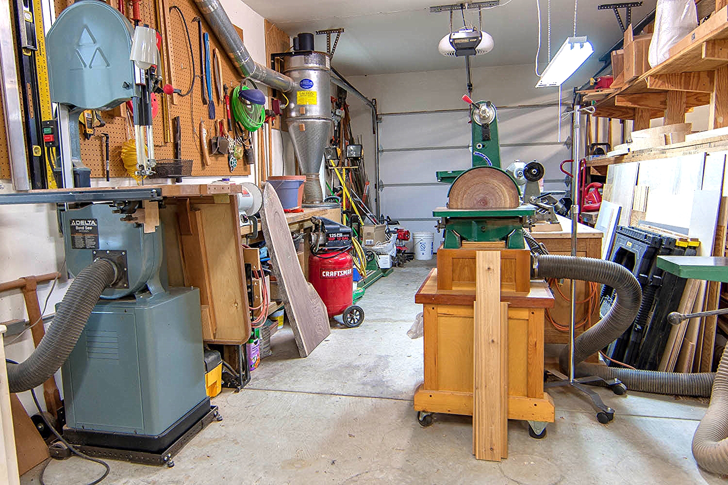 Shop looking SE; bandsaw, oscillating spindle sander, workbench 3, disc/belt sander, lathe, lumber rack
