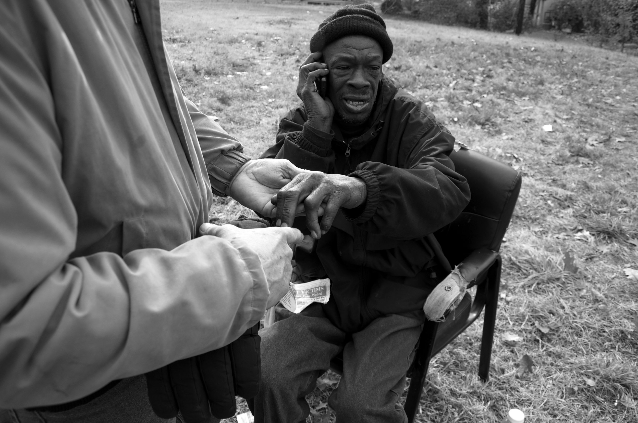  Willie Brown calls a lawyer as Dr. Anthony Martinez examines the homeless man. Brown fell down an open sewer, scraped his hands and legs, and sprained his knee. &nbsp; 