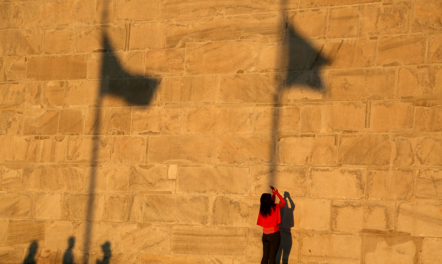  A woman in red takes a picture of the Washington Monument with her cell phone on October 8, 2014. Visitors congregate around the monument as the sun sets in Washington, D.C. 