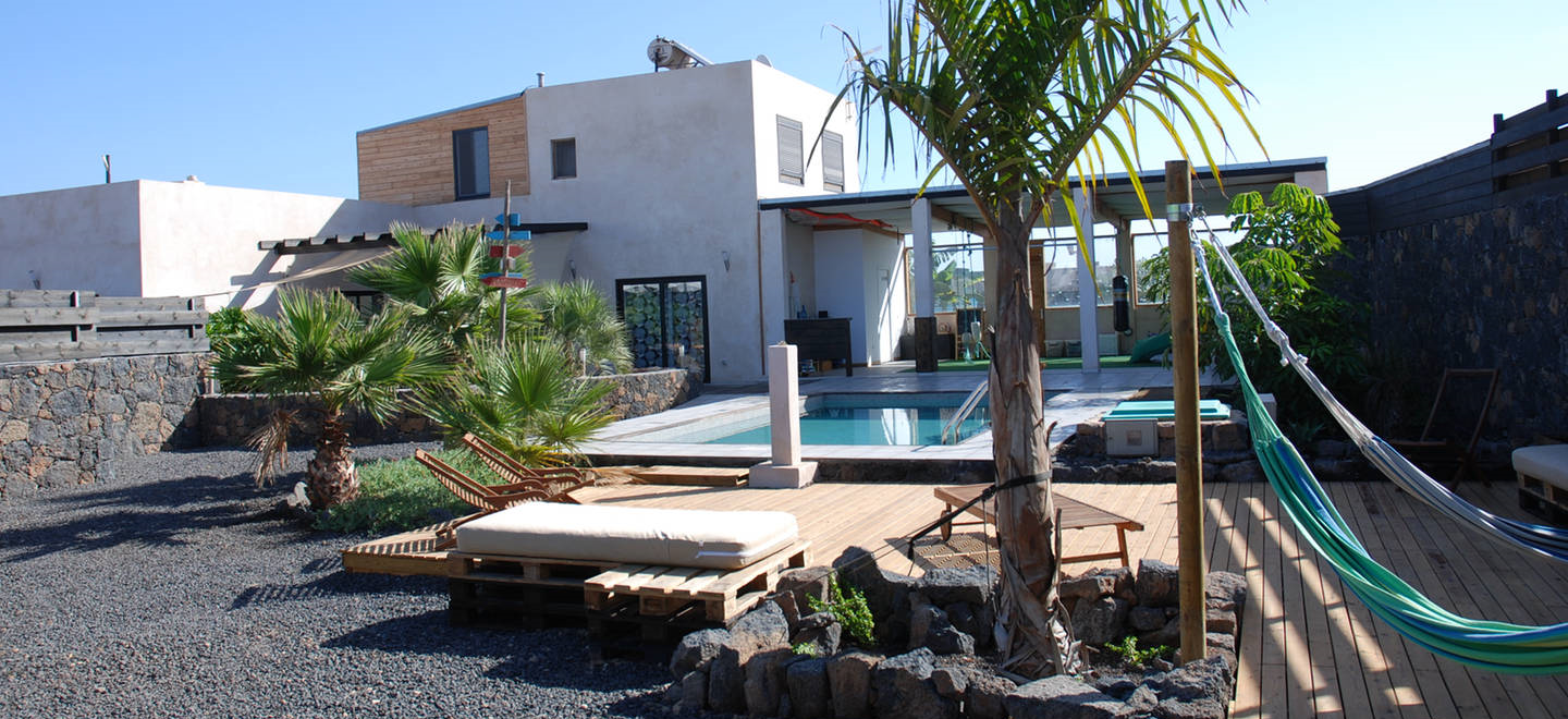 I CAMP vengono ospitati presso Black Rocks Villa, una grande casa di nuova costruzione con piscina, adatta ad ospitare fino a 15 persone. La villa è composta da 5 camere da letto. La villa inoltre dispone di: un’area comune con divani, televisore e dvd, una sala per i pasti, una grande cucina attrezzata, un’ampio spazio esterno per il tempo libero, zona pranzo esterna ombreggiata, una piscina, un'area relax, un ricovero per riporre il materiale sportivo, un’area di lavaggio per i surf e le mute, servizi e doccia esterni, lavabo esterno, BBQ. La villa si trova nel centro del paesino di Lajares, ai piedi dei vulcani. Una posizione strategica per arrivare in meno di 15 minuti su qualsiasi costa dell'isola e raggiungere facilmente i migliori spot per il surf. 