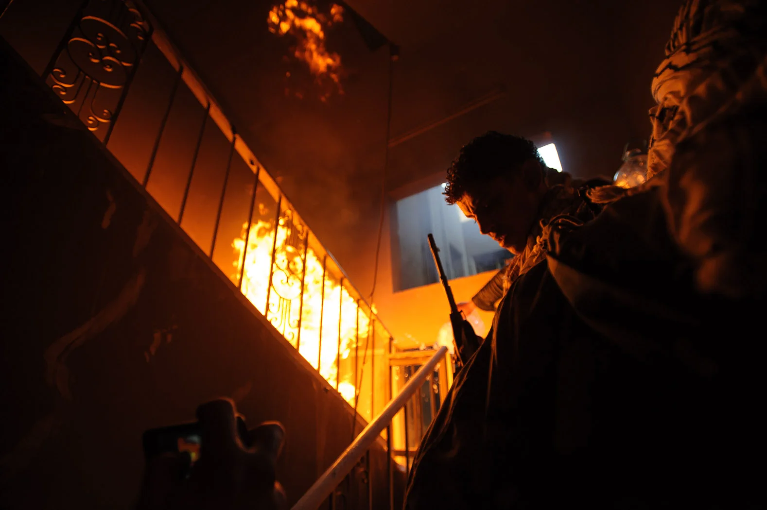 A Libyan rebel mounts a staircase in a building under attack in Misrata, amidst the fire from a rocket-propelled grenade