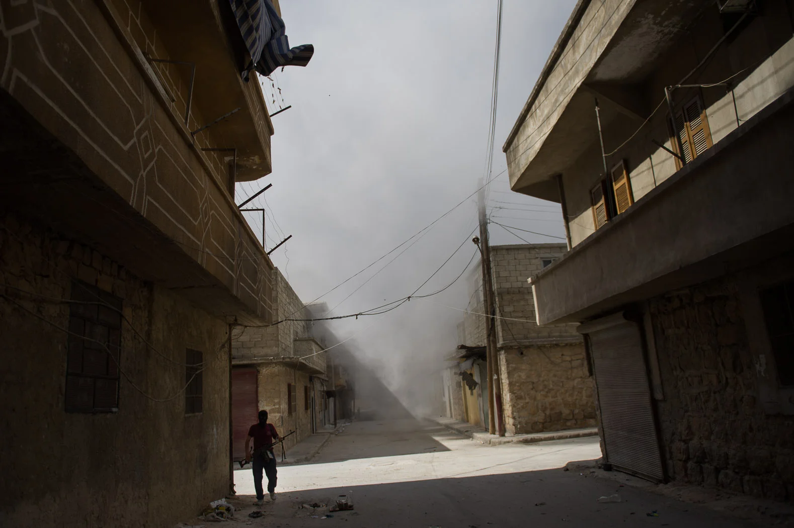 A Syrian rebel walks through a street under shelling in Aleppo's Salaheddine district.