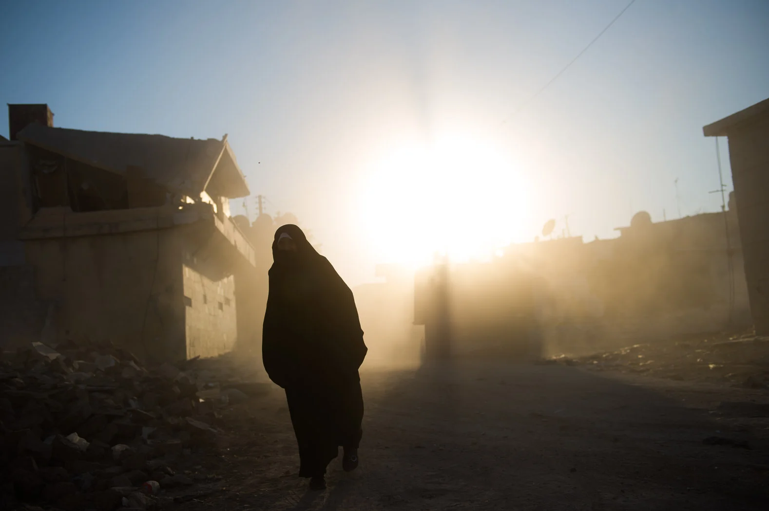 A lady dressed in a burka walks through the debris from an aerial bombing raid in Azaz, Syria