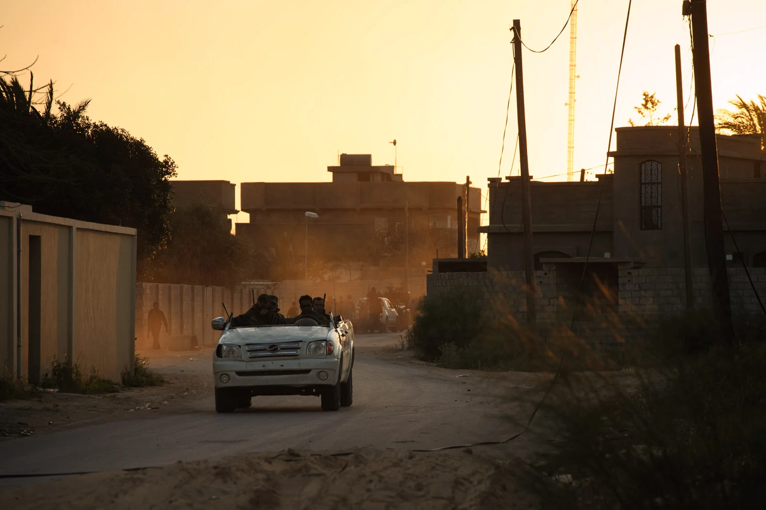 Men speed away from heavy shelling through a residential district on the edge of Misrata in a converted truck, loaded with weapons.