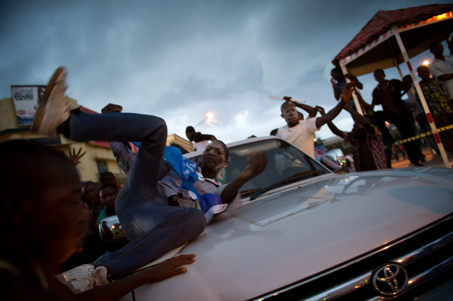 A supporter of incumbent President Joseph Kabila rolls over a car as he celebrates Mr. Kabila's win.