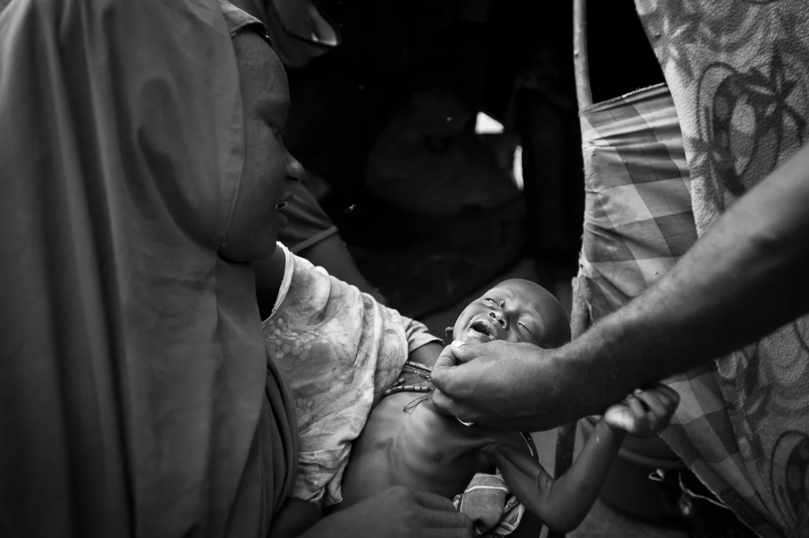 Sa'cdiya Al Nur with her one and a half year old son, Hussein. They left their home in Bay region due to the drought, coming to Mogadishu in hope of humanitarian assistance. Hussein is suffering from severe acute malnutrition, and NGO staff here fear he may die tomorrow, or after tomorrow. "He is too weak to even brush away the flies" says an aid worker, one of very few working here. "Before the drought, we had nothing, now we still have nothing" says Sa'cdiya, at a loss for what she to save her child.