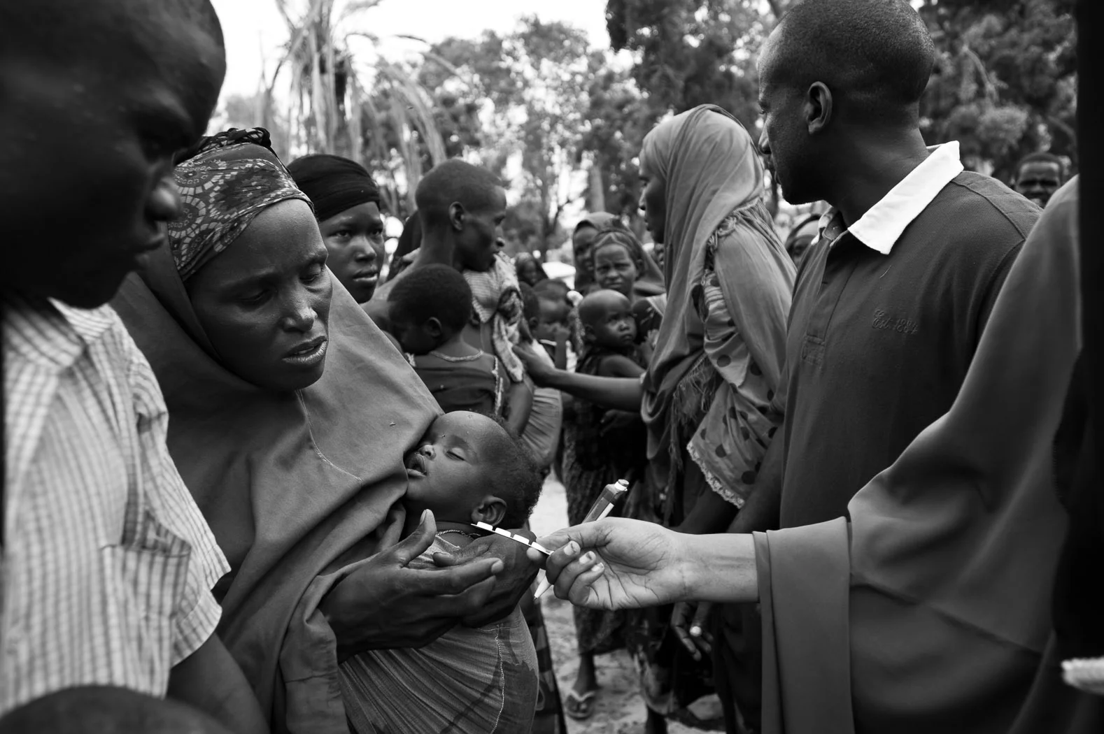 Mothers queue with their children for health care given by Concern Worldwide staff at the Viishio Governo IDP camp in Mogadishu. With no sanitation in the camp, and with little food, the health levels are dire. Staff here were distributing zinc tablets for diarrhoea, de-worming tables, pain-killers and oral rehydration solution.