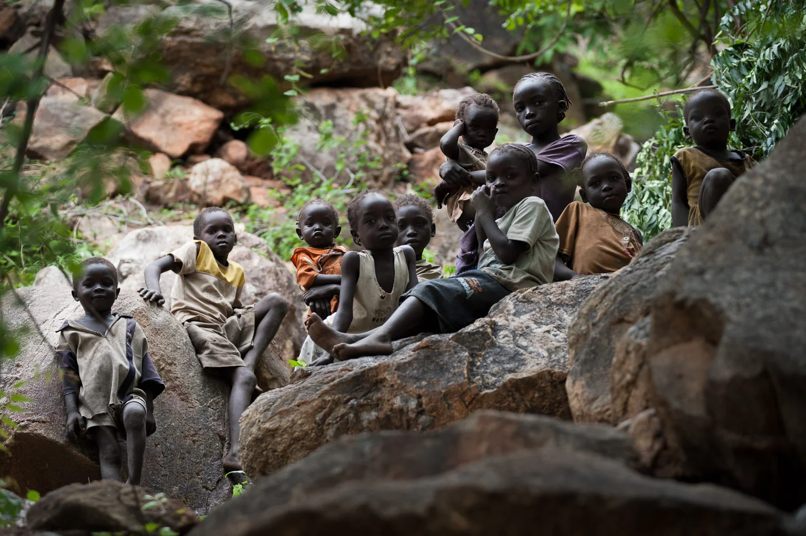 In the hills surrounding the village of Kauda, in the heart of the Nuba mountains, children spend their days hiding amidst the rocks. Their families fear the aerial bombardments and so put them here together whilst they try to work the fields.