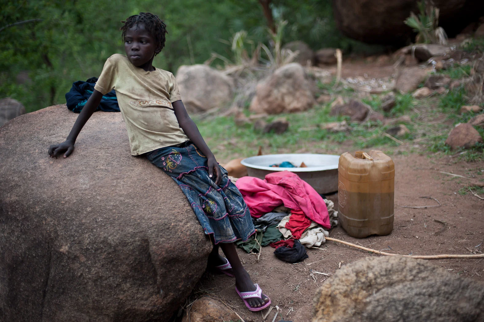 A girl stands next to her family's washing near a cave in the Nuba mountains. Life has taken an almost everyday quality in the hills above Kurchi, as the families taking refuge here continue their daily chores amongst the rocks.