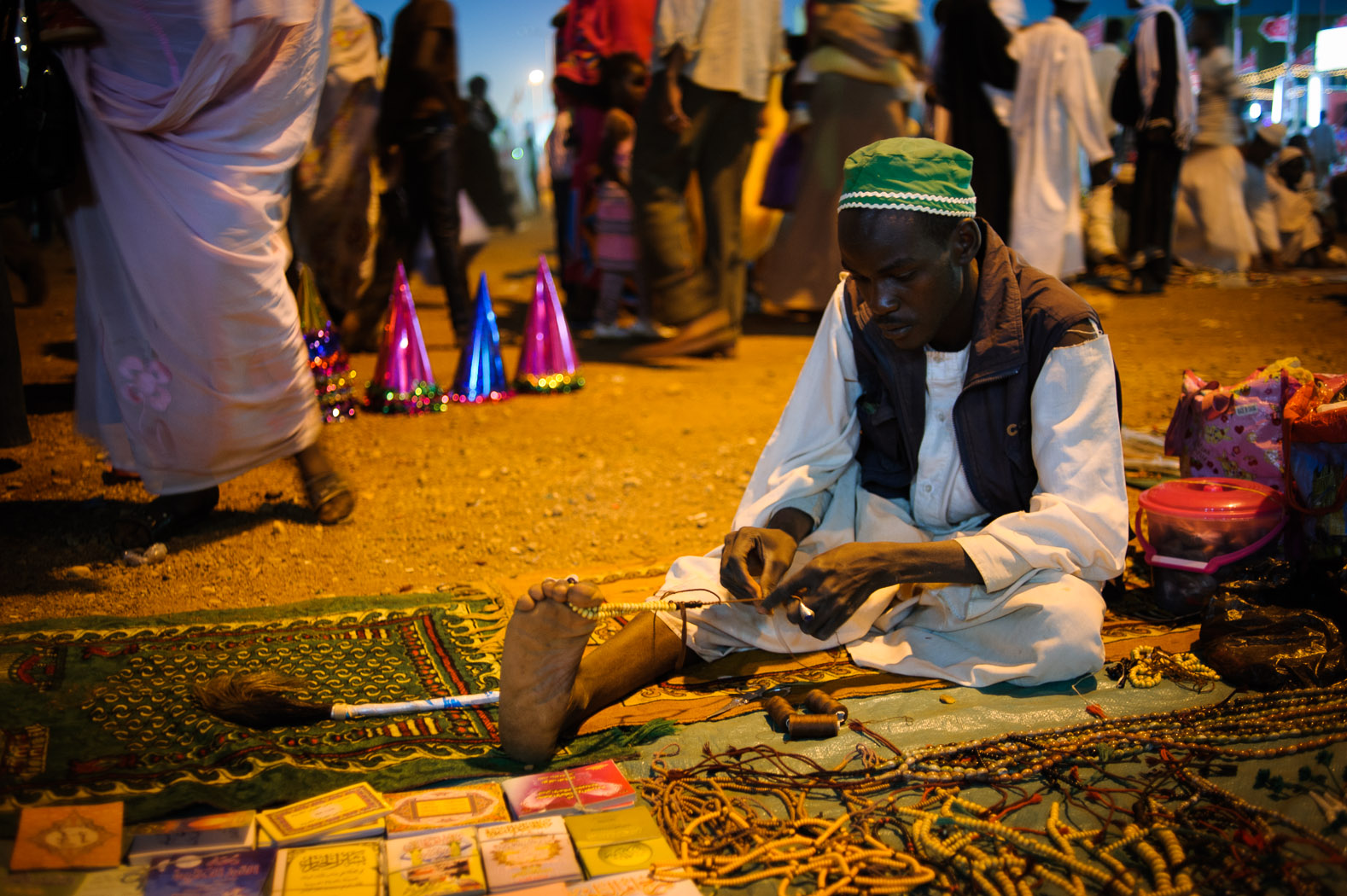 A Sudanese man threads Islamic prayer beads to sell during Mawlid celebrations.