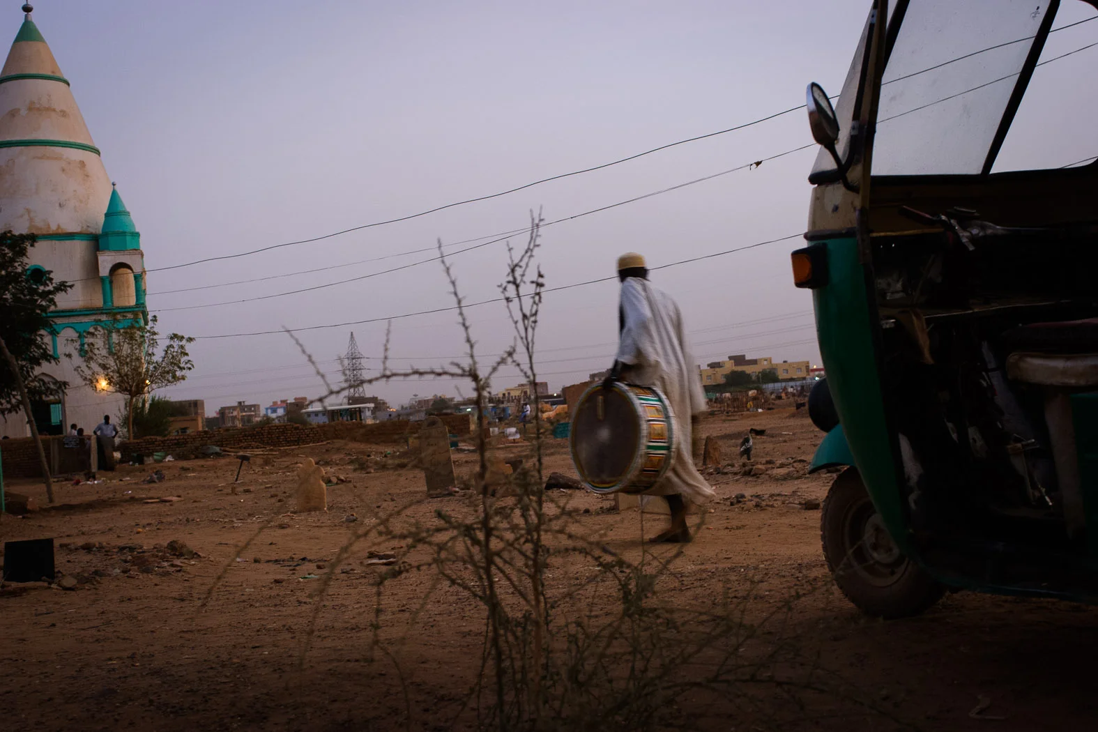 A Sudanese sufi carries a drum towards a shrine in Omdurman, Sudan