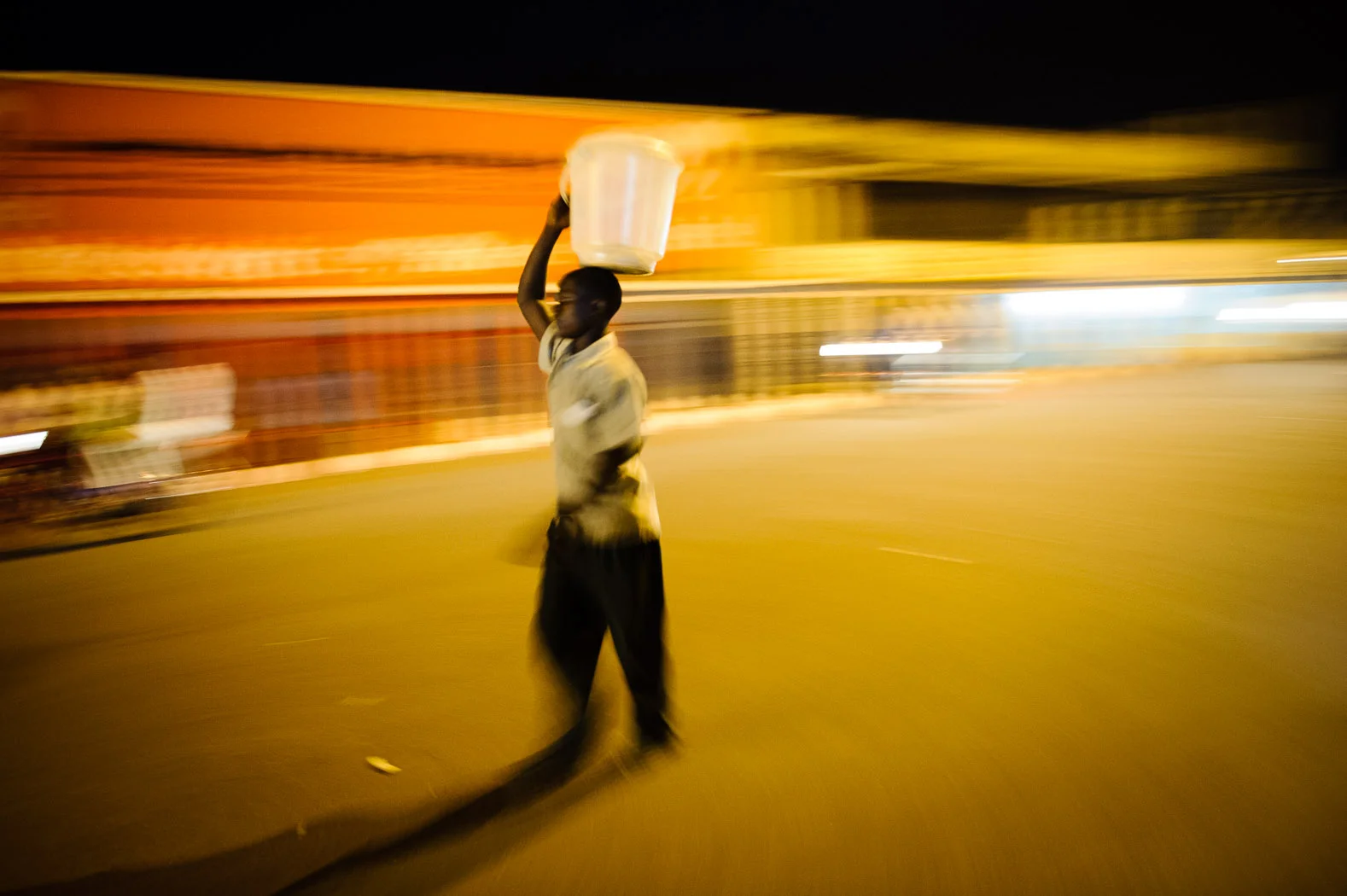 A boy carries an empty bucket used to sell food after a day of working the streets in Goma