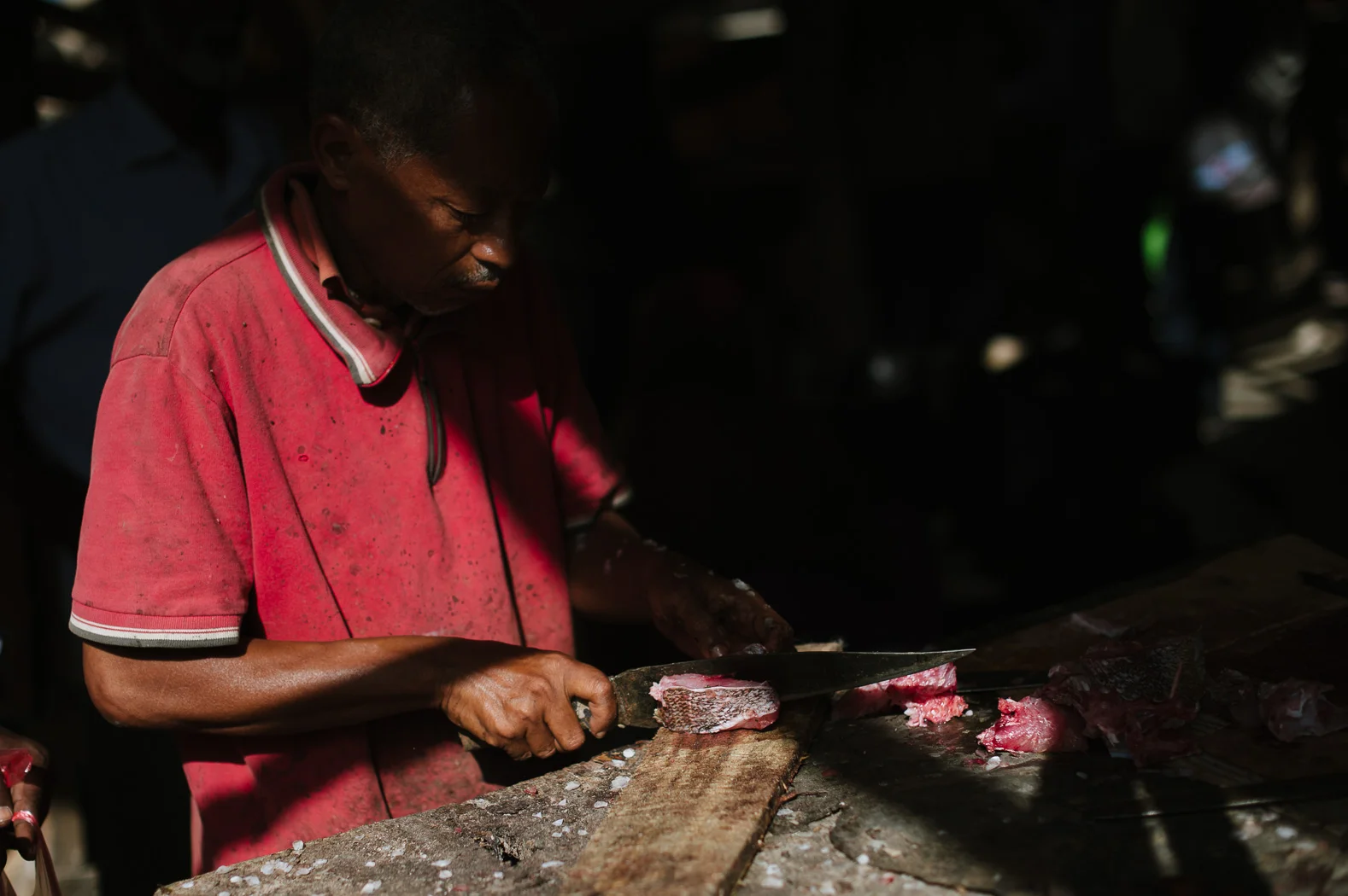 A fishmonger prepares a fish in the market