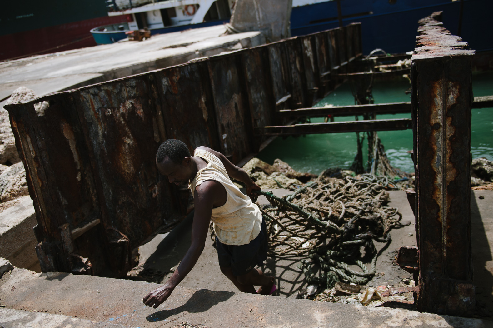 A man hauls a cargo net from a transporter boat in the port