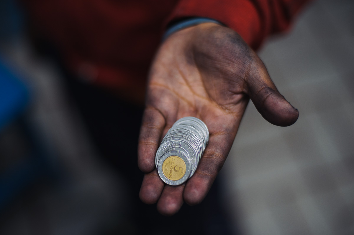Ruben Flores (13) holds the money he earned from a day's shoe-shining, 26 Bolivianos, just under $4 (USD), pictured at his home in La Paz, Bolivia.