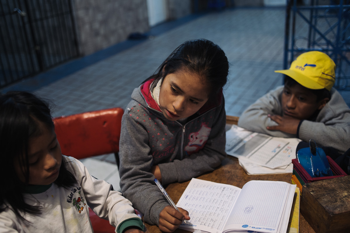 Edith Flores (10, centre) helps her sister, Rayna (7) with homework as Ruben watches in the "New Day Foundation", a centre for shoe-shiners where the family lives, in La Paz, Bolivia.