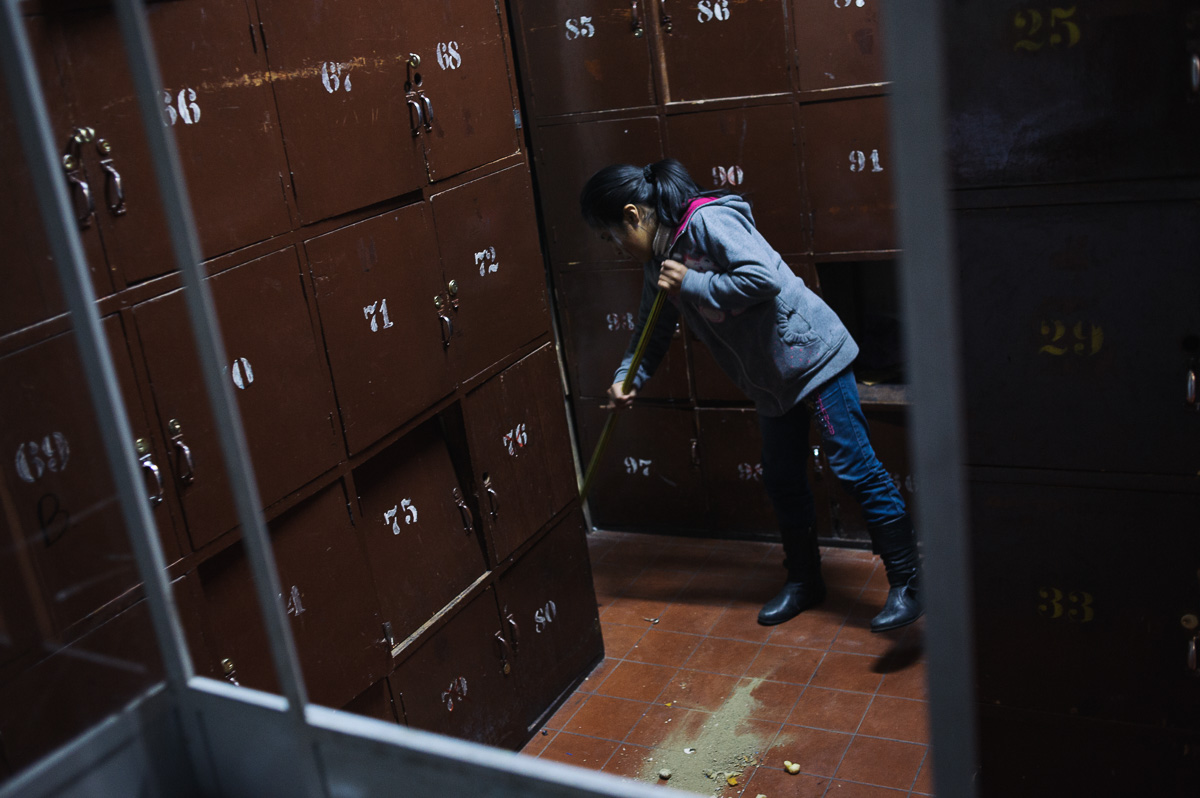 Edith Flores (10) sweeps the floor of the locker-room in the "New Day Foundation", a centre for shoe-shiners in La Paz, Bolivia. Edith's brother, Ruben (13), and her father, Jonny, both work as shoe-shiners -- a highly stigmatised. Edith does not formally work for pay, but regularly helps her mother clean the centre, where she is care-taker and the family live.