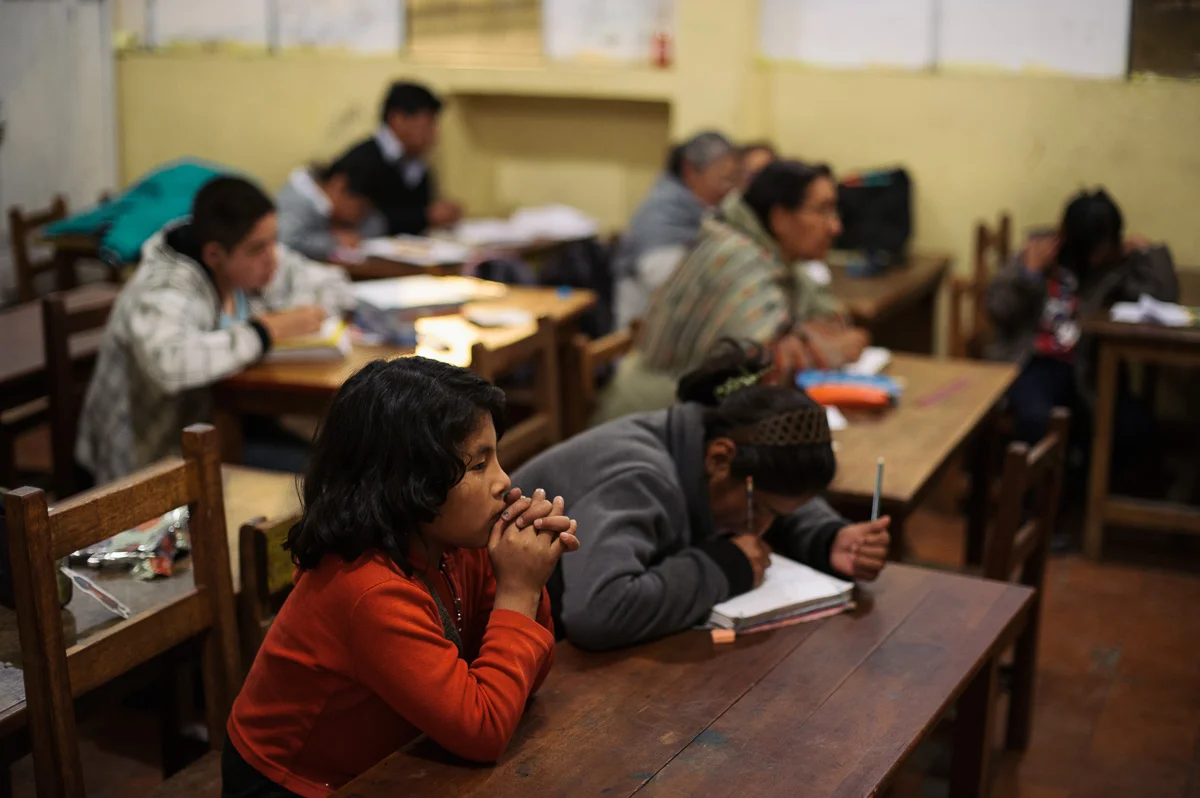 Pupils sit during a night-school class in La Paz, the Bolivian capital. The Bolivian law dictates that child workers must still attend school, and many children in this neighbourhood attend nightschool to allow them to work during the day. The children sit alongside adults who are belatedly getting a primary education.