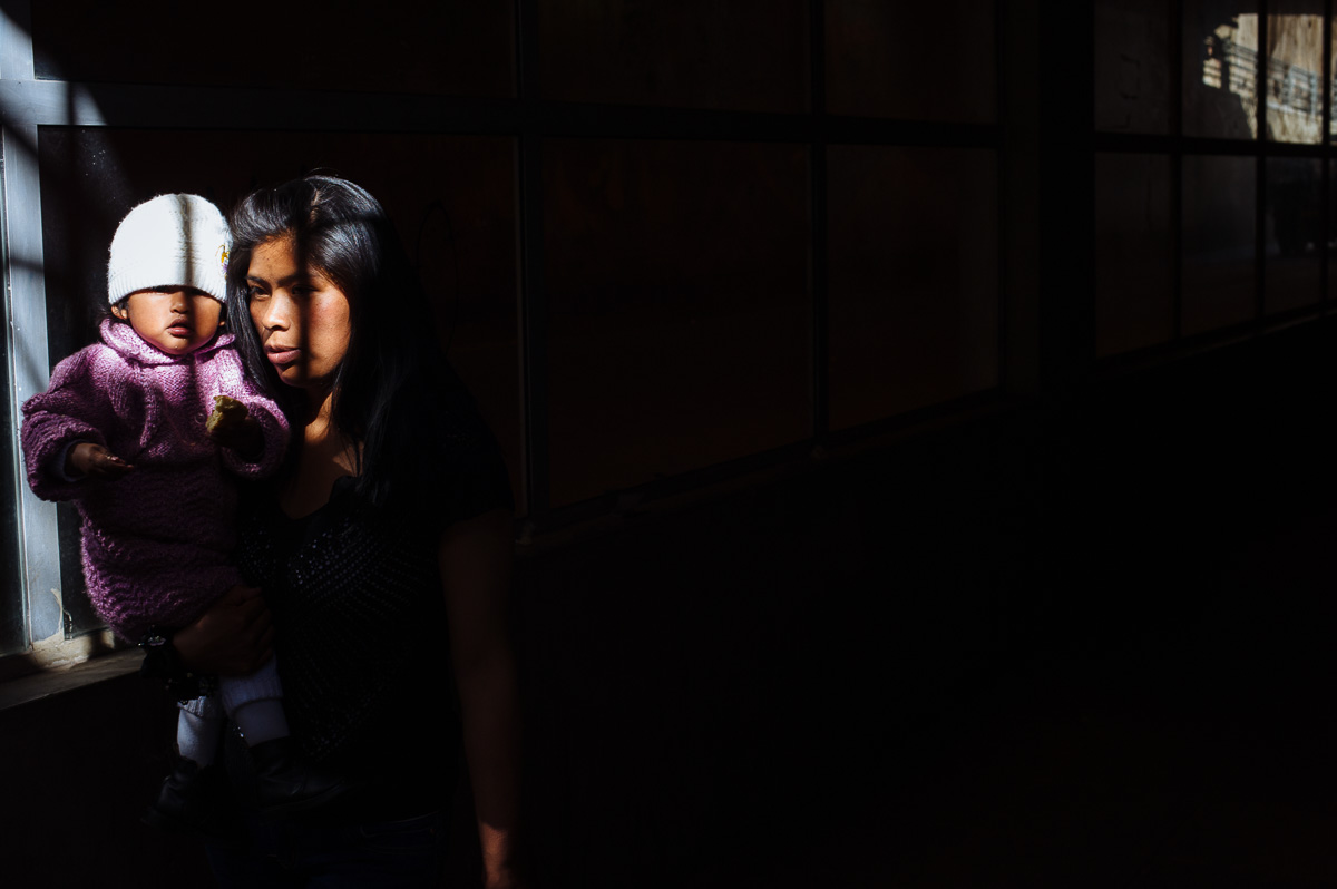 A woman carries her young child through an underpass frequented by young shoe-shiners in La Paz, Bolivia.