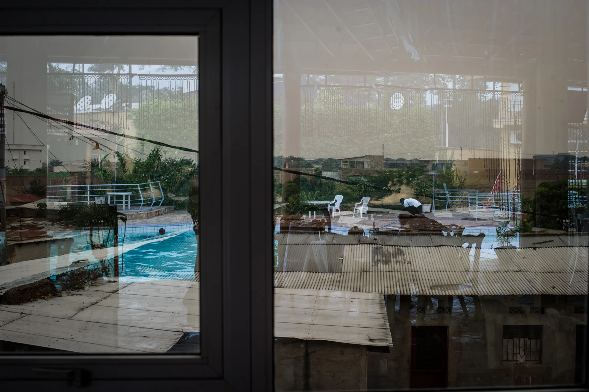 The swimming pool at a $100 a night hotel is seen reflected in windows overlooking the tin-roof slum in the Buyenzi neighbourhood of Bujumbura, Burundi, on June 25, 2015. The gap between rich and poor in the Burundian capital can seem stark.