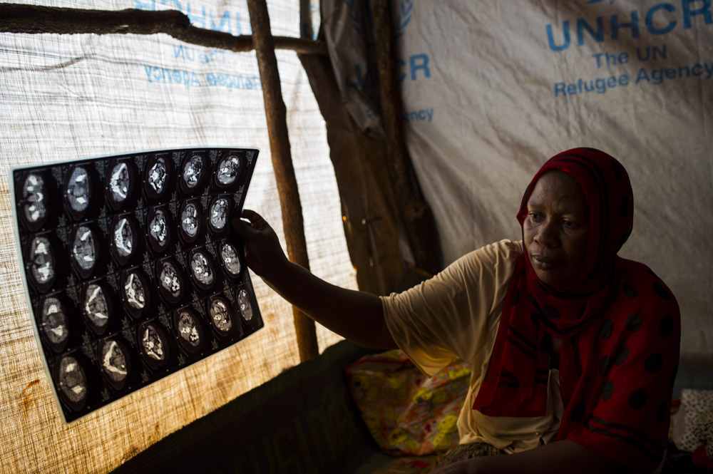 Ester* (44), holds up x-rays in her room in a mass shelter in the Nyarugusu refugee camp in Tanzania on March 27, 2016. Ester suffered from breast cancer and had a mastectomy several years ago, and is still being treated by chemotherapy. Doctors here told her she needs to eat well and avoid sick people, but she shares this room with another lady (and her children) who is suffering from typhoid and malaria, and she doesn't receive any extra food, nor any fruit or vegetables.
*Name has been changed to protect their identity.