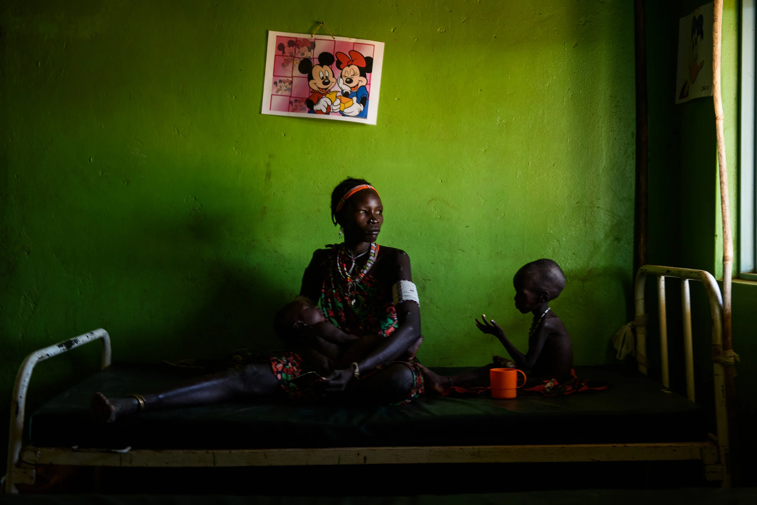Lohali Lokwar holds her eight month old son, Lokwai Lokwar, beside Lonya Lokwar (2) in the stabilisation ward of the Riwoto primary health-care centre in Kapoeta North, South Sudan, on May 24, 2017. Lonyya was been admitted into the ward yesterday, suffering from severe acute malnutrition, complicated by diarrhoea and vomiting. Lohali says his condition started as a stomach ache. As part of his treatment he will receive therapeutic milk every three hours.
Photo by Phil Hatcher-Moore - UNICEF