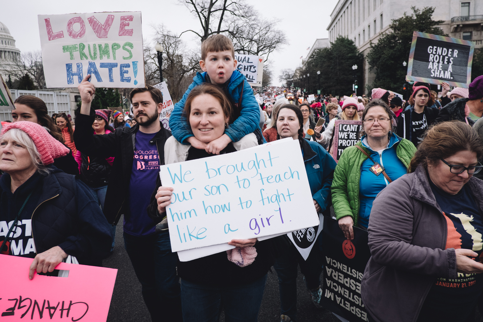Jenny O'Neil holds her son, Benjamin, 5, on her shoulders as they make there way past the Capital building to the rally.
