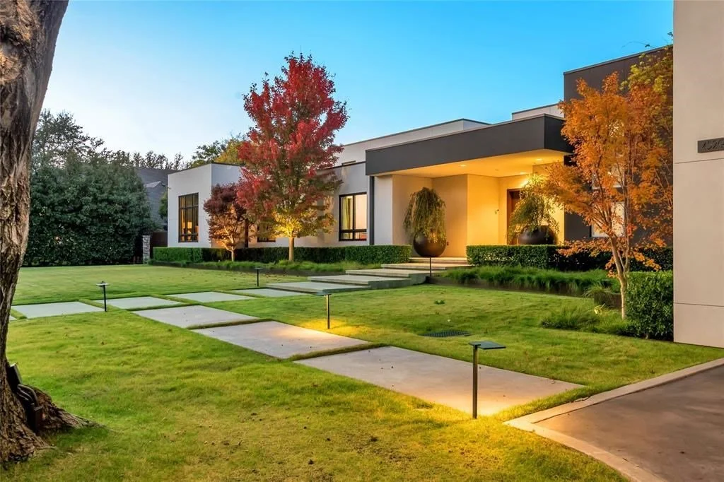 Modern house with a well-maintained front yard, pathway lights, green lawn, and trees.