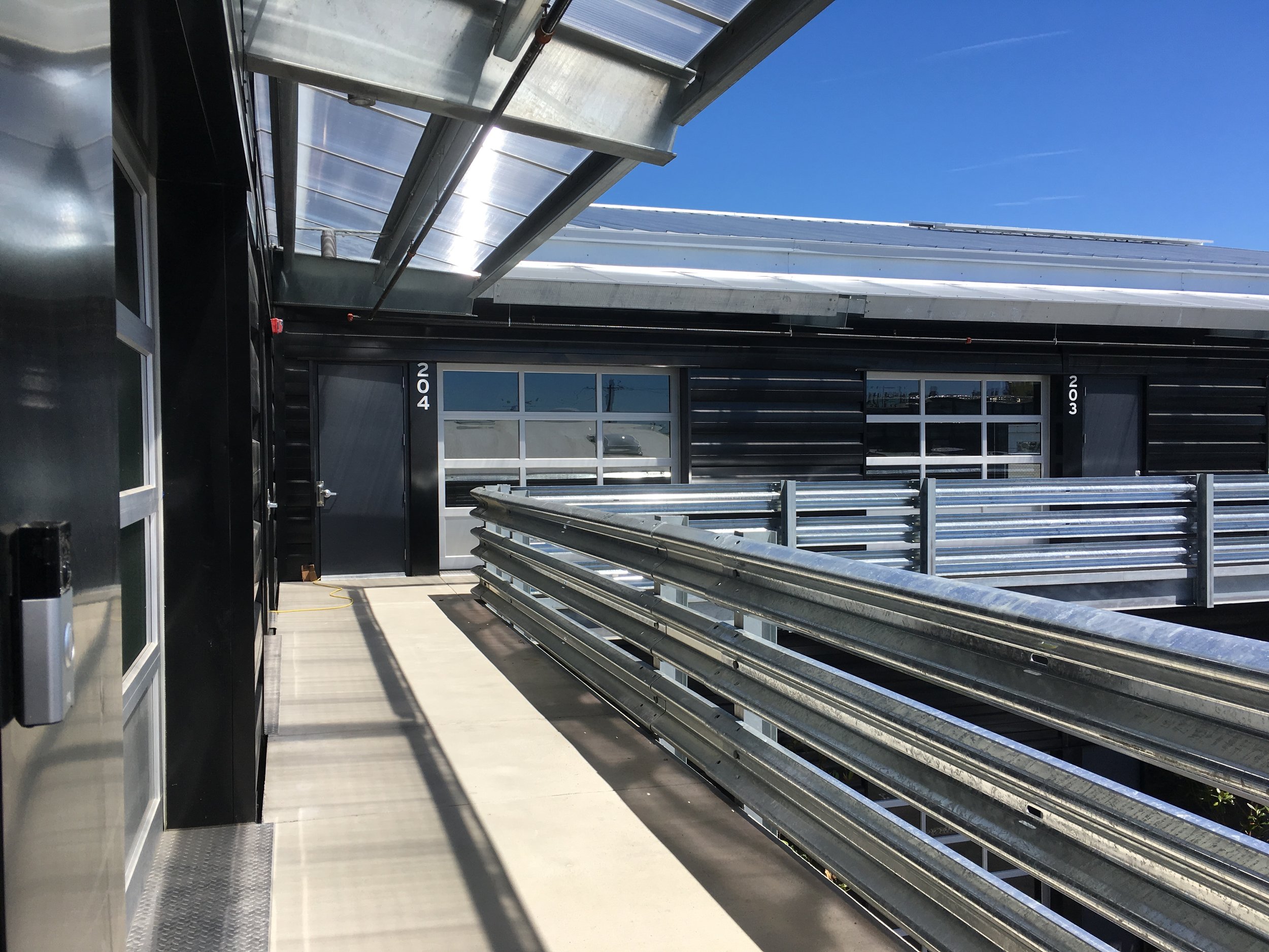 View north along upper balcony walkway. The owner sourced the guardrails in front of roll-up doors, portions in front of the garage doors are removable for fork-lift deliveries from the parking lot below.