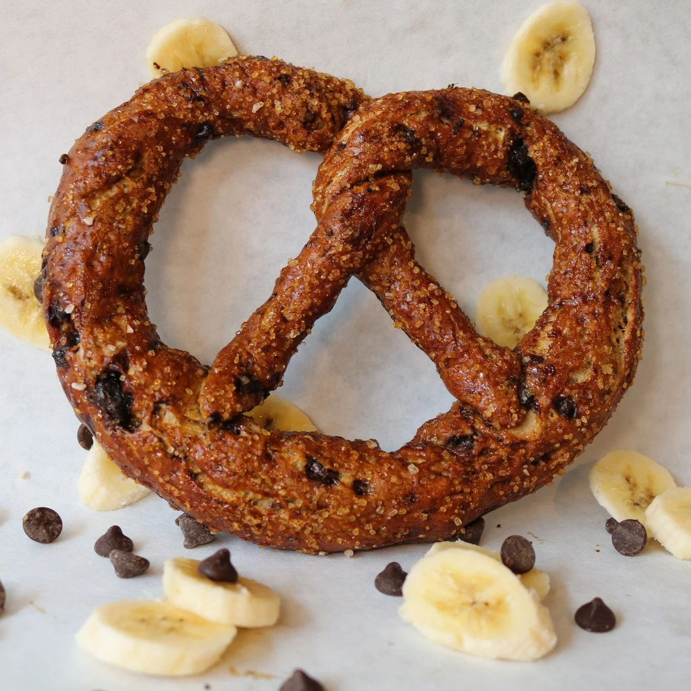 🍌🍫 Banana Chocolate Chunk is back and better than ever! 

We packed 16 fresh bananas into this batch 😳, mixed in chopped dark chocolate, doubled the sweetness, and added a splash of vanilla for good measure. Before baking, each pretzel gets finish