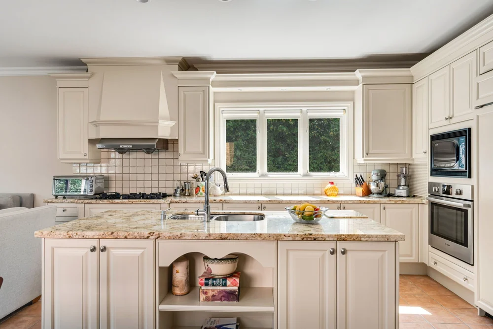 Kitchen detail showing granite counters, gas range and built-in wall ovens