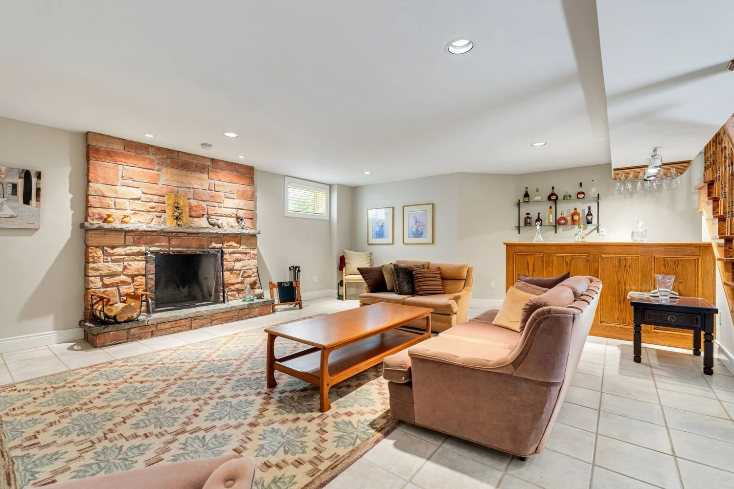 Lower level family room with floor-to-ceiling stone fireplace and built-in bar