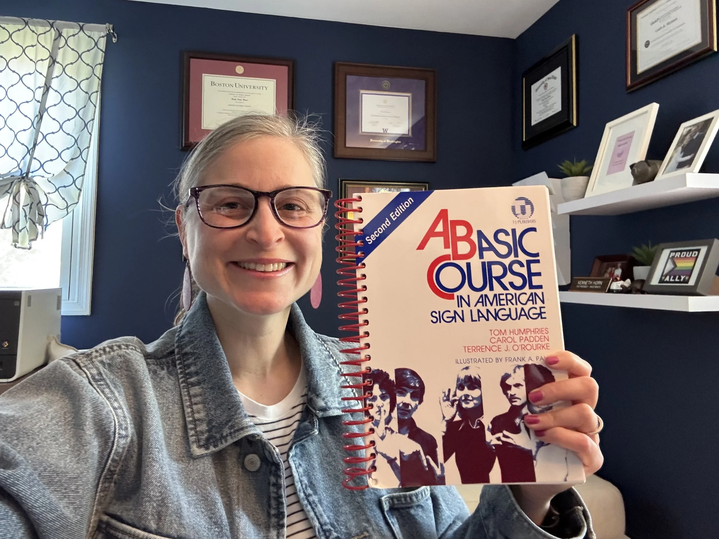 Leah takes a selfie with her ASL class textbook.