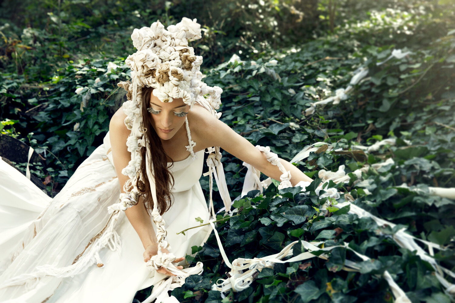 woman wearing knotted headpiece rising from ivy covered ground; conceptual fashion editorial by photographer Hanna Agar