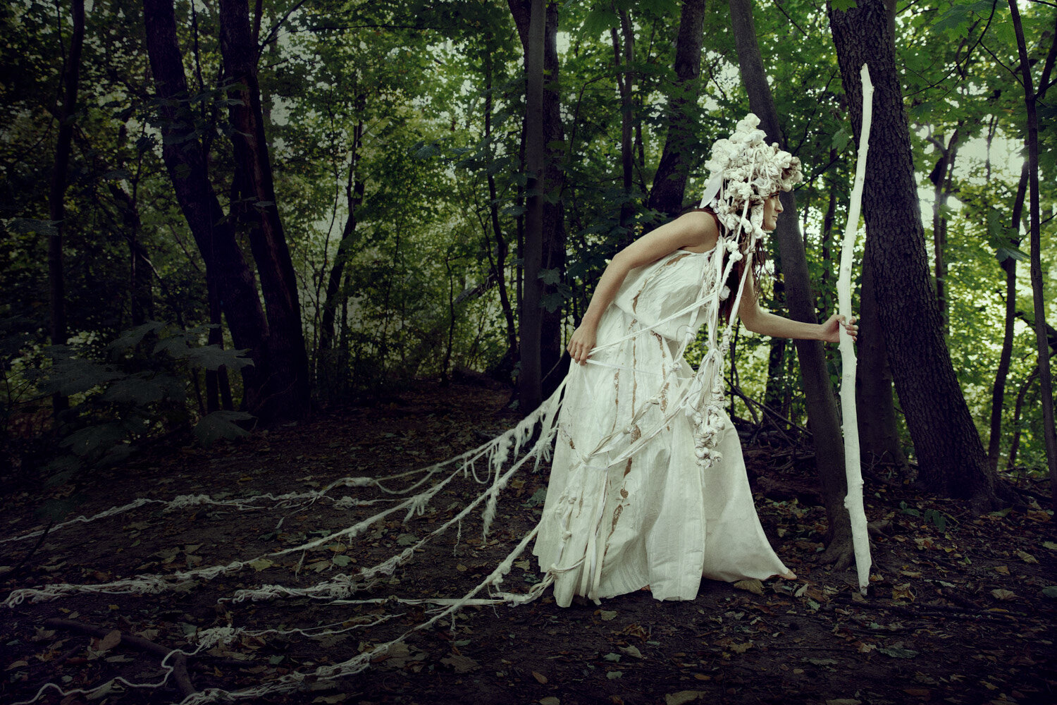 moody conceptual fashion image of elaborated knotted headpiece and garment in the woods