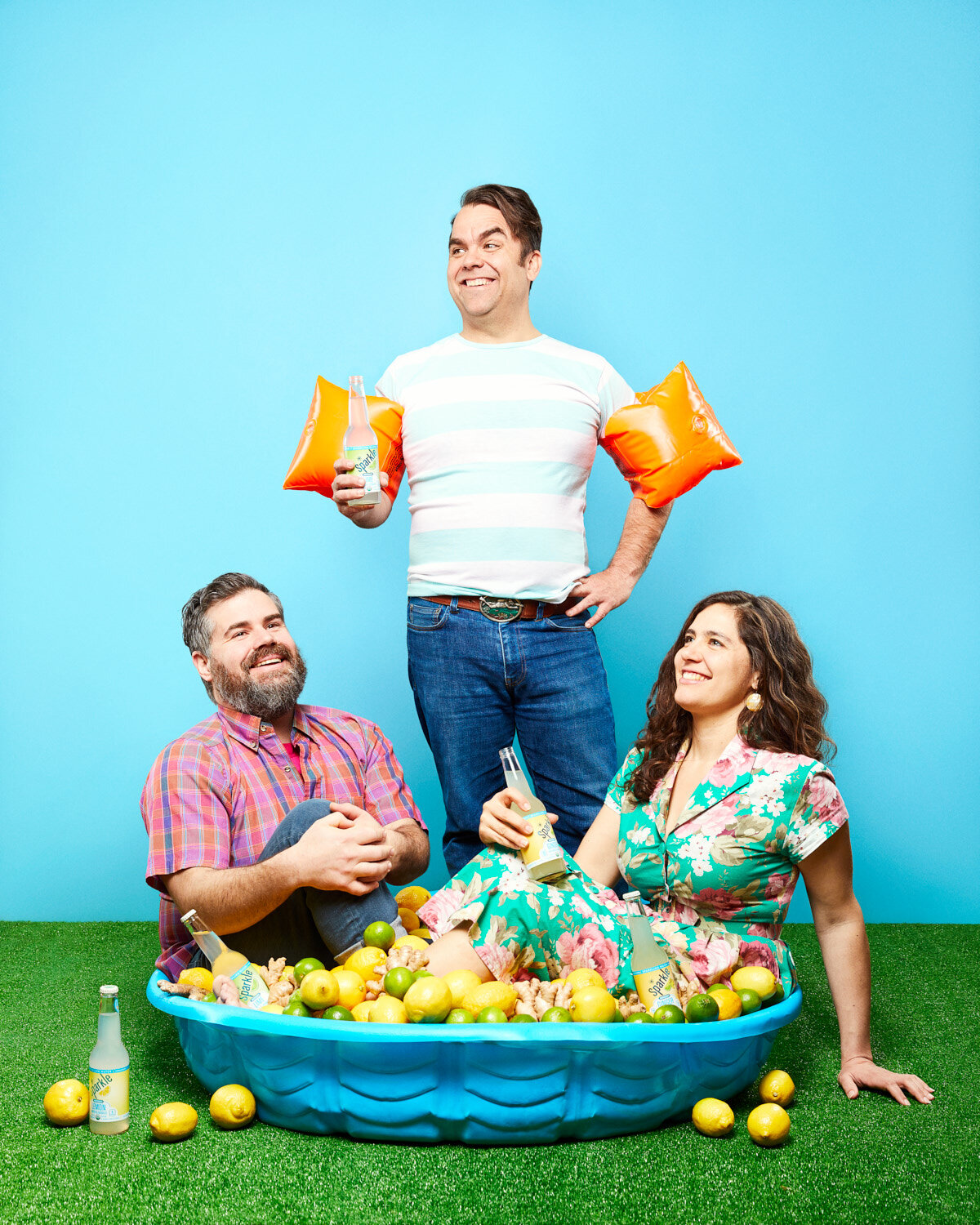 Quirky commercial portrait of the WiscoPop! team sitting in a kiddy pool of produce.