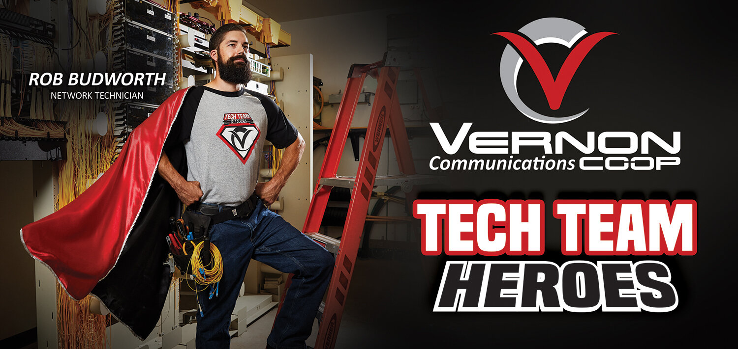 Network technician in red cape posed as superhero for a creative advertising campaign created for billboard ads for Vernon Communications Coop.