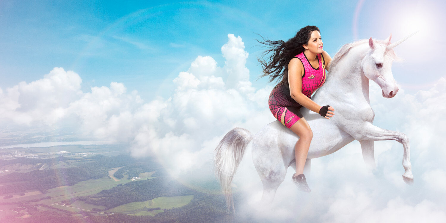 Creative product photography: Athlete wearing colorful triathlon kit by Venganza rides a unicorn through the sky.