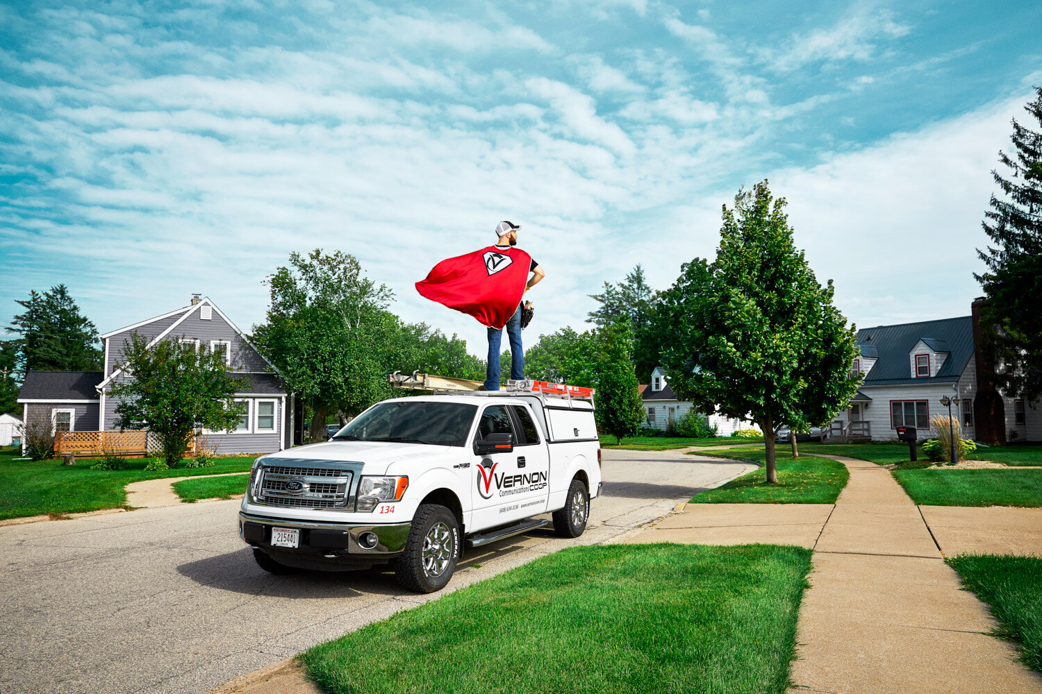 commercial photography: network technician heroically posed on top of a truck in Viroqua, WI neighborhood