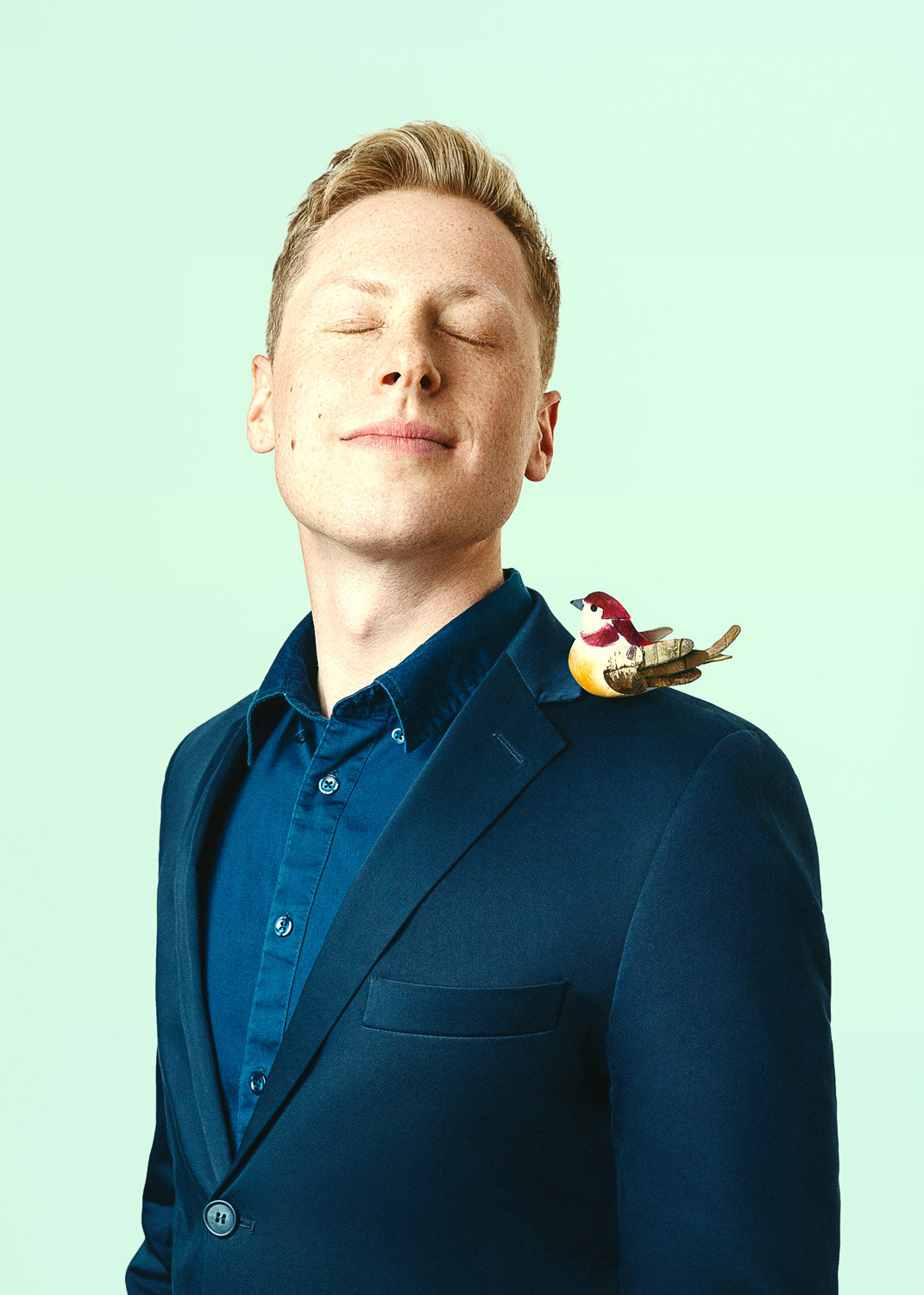 creative portrait of magician Ben Seidman eyes closed with a bird on his shoulder by portrait photographer Hanna Agar