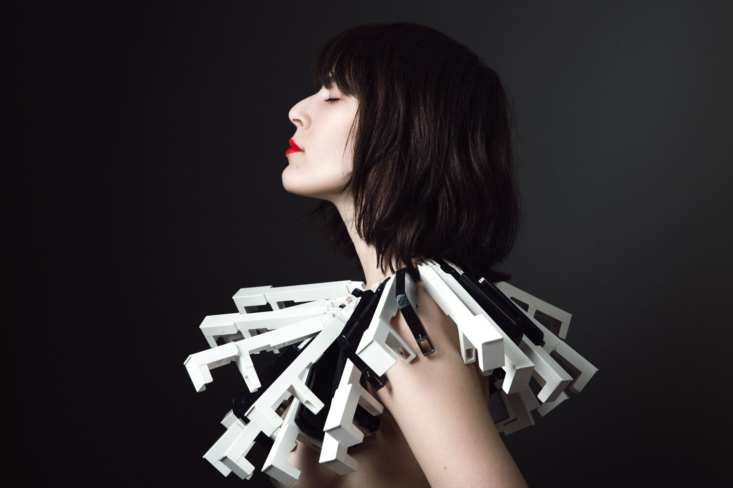 dark studio portrait of musician Janna Pelle wearing piano key necklace by creative portrait photographer Hanna Agar
