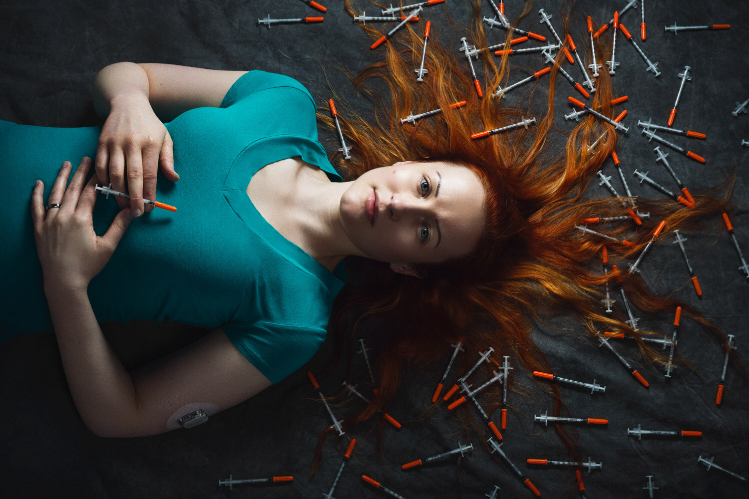 moody portrait of Asha Brown, founder of We Are Diabetes laying on the floor surrounded by insulin needles