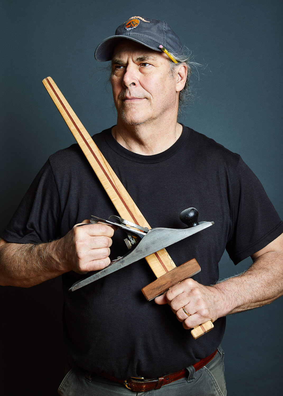 portrait of woodworker holding wooded sword and hand plane