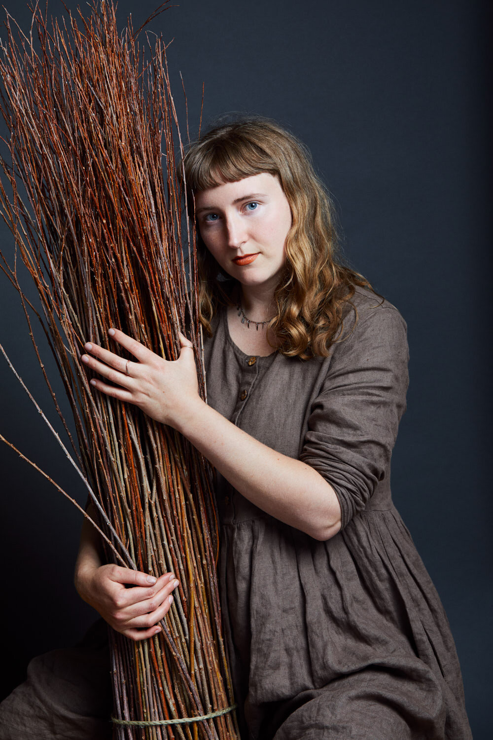 beautiful studio portrait of basket weaver holding bundle of willow by portrait photographer Hanna Agar
